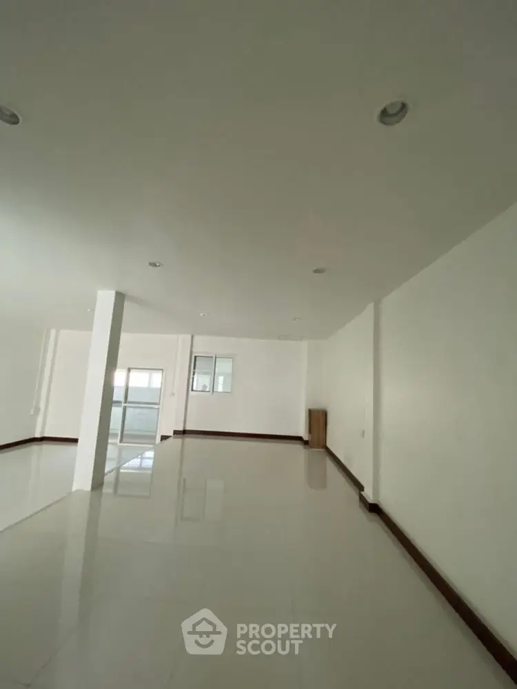 Spacious empty room with glossy tiled floors and white walls, ideal for customization.