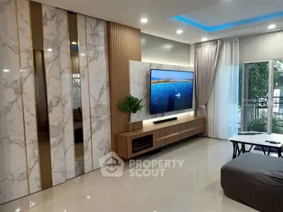 Modern living room with stylish decor, large TV, and sliding glass doors leading to a balcony.