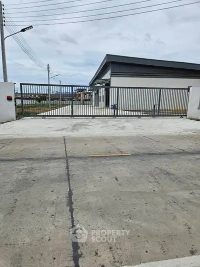 Modern industrial building with secure gated entrance and spacious concrete driveway.