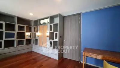 Spacious modern living room with built-in shelving and elegant wooden flooring.