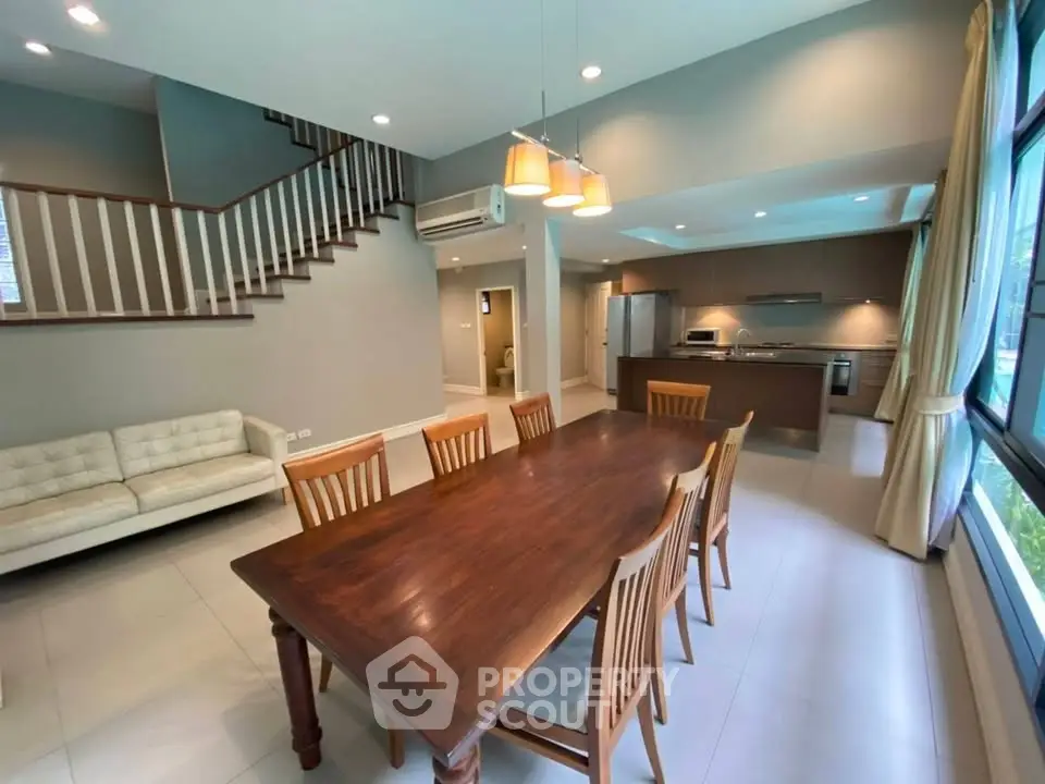 Spacious open-plan living and dining area with modern kitchen and elegant staircase.