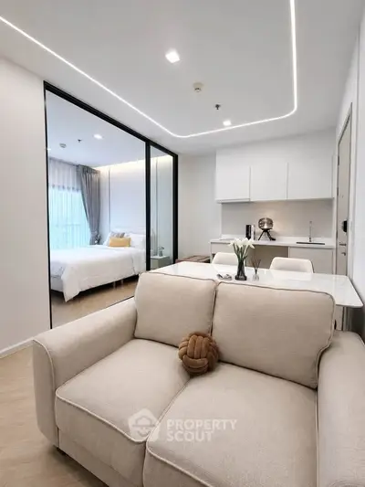 Modern open-plan living room with cozy sofa and sleek kitchen in a stylish apartment.