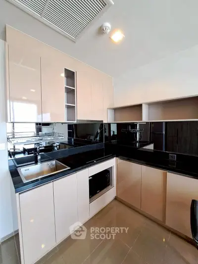 Modern kitchen with sleek cabinetry and black countertops in a stylish apartment.