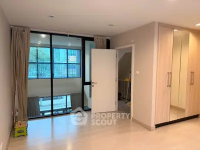 Spacious modern room with large windows and built-in wardrobe, perfect for urban living.