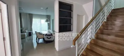 Modern interior with open living and dining area, featuring elegant staircase and natural light.