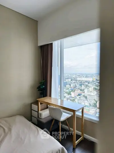 Modern bedroom with stunning city view, featuring a sleek desk and chair by the window.