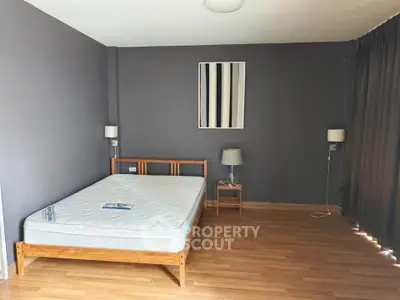 Spacious bedroom with modern decor and natural light, featuring a minimalist design and wooden flooring.