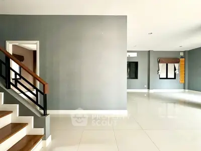 Spacious modern living room with sleek staircase and large windows