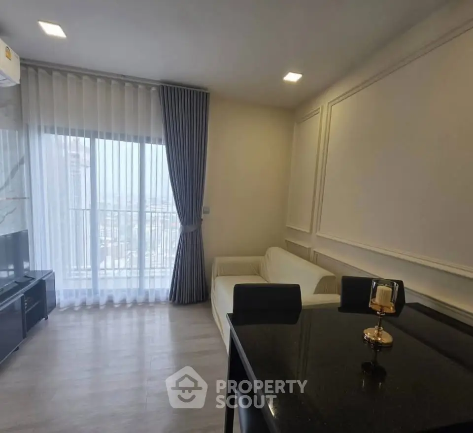 Modern living room with large window and elegant decor in a high-rise apartment.