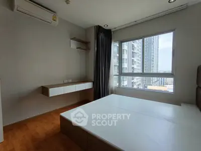 Modern bedroom with large window and city view in high-rise apartment