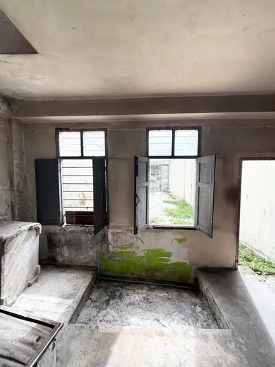 Rustic interior with open windows and weathered walls, offering potential for renovation.