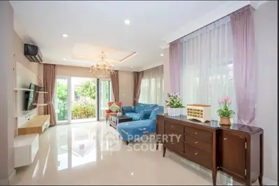 Spacious living room with elegant decor and garden view, featuring a chandelier and modern furniture.