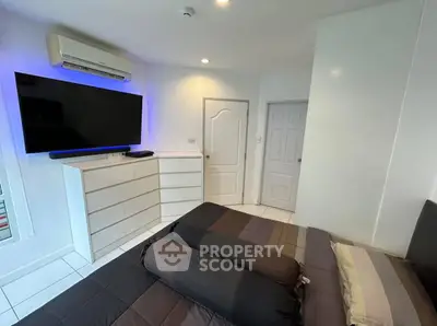 Modern bedroom with sleek design, featuring a large TV and stylish dresser.