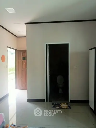 Compact interior with visible bathroom entrance and open door to exterior