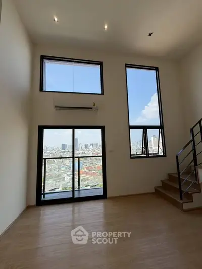 Spacious modern living room with large windows offering stunning city views and natural light.