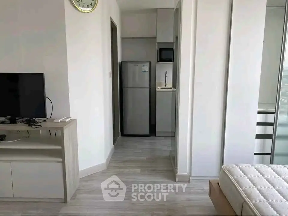 Modern apartment interior with sleek kitchen and cozy living area, featuring a stylish fridge and TV setup.