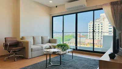 Modern living room with large windows and city view, featuring stylish furniture and natural light.
