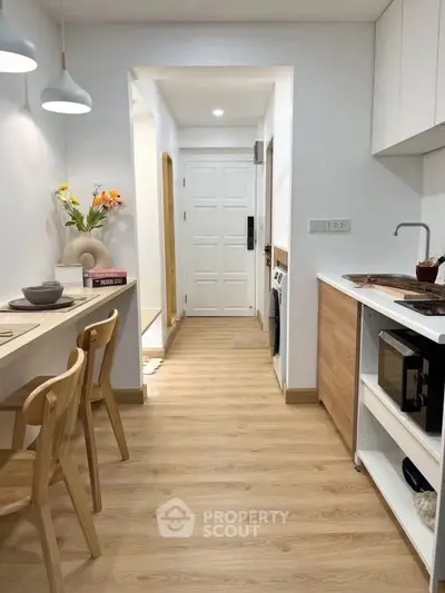 Modern kitchen with open layout and stylish wooden flooring, featuring sleek appliances and elegant lighting.