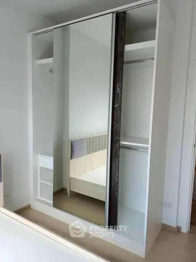 Modern bedroom with sleek mirrored wardrobe and minimalist design.