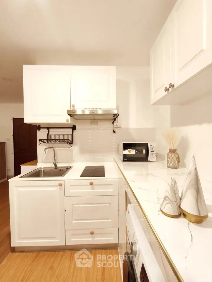 Modern kitchen with white cabinets and marble countertops, featuring a sleek design and efficient layout.