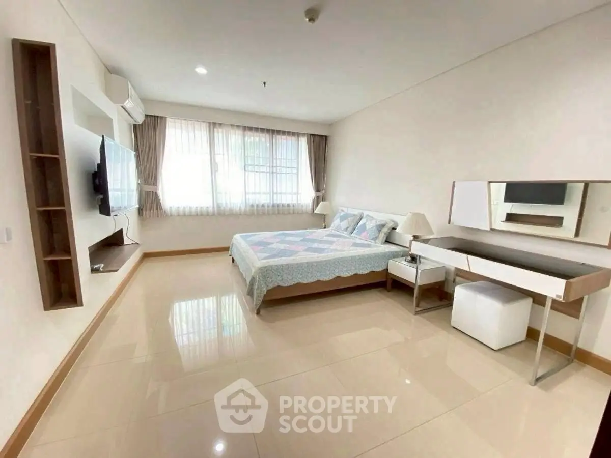 Spacious bedroom with modern decor and natural light in a stylish apartment.