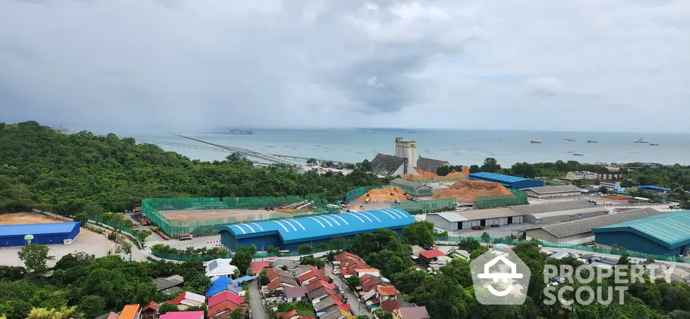 Stunning coastal view with lush greenery and industrial buildings near the ocean, perfect for development.