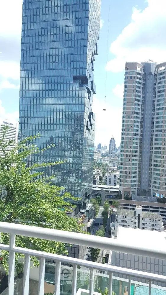 Stunning cityscape view from a high-rise balcony with modern skyscrapers and lush greenery.