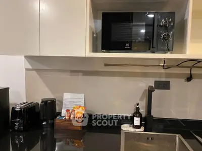 Modern kitchen with sleek black countertop and built-in microwave, featuring stylish appliances and organized layout.