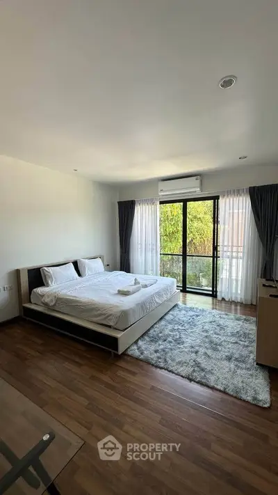 Spacious bedroom with modern decor and large windows offering natural light.