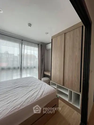 Modern bedroom with large window and wooden wardrobe in a cozy apartment.