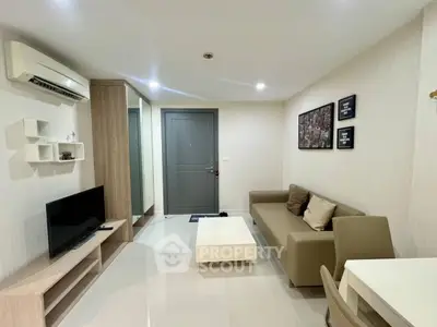 Modern living room with sleek furniture and neutral tones, featuring a cozy sofa and wall-mounted TV.