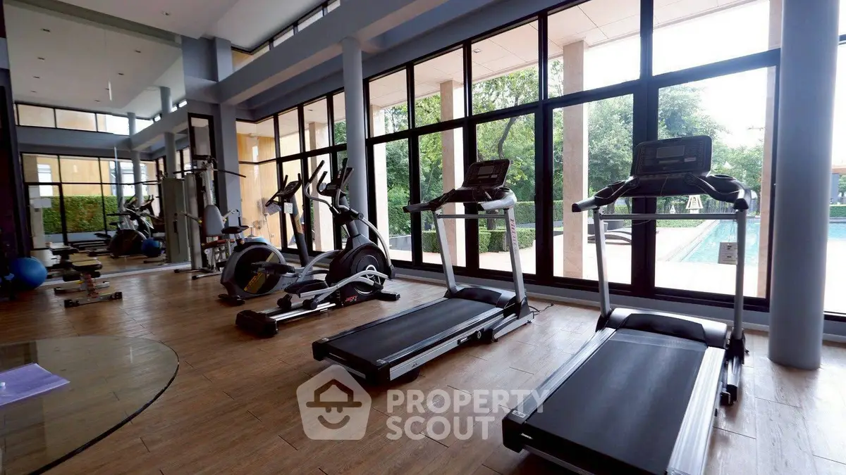Spacious gym with modern equipment and pool view in luxury property