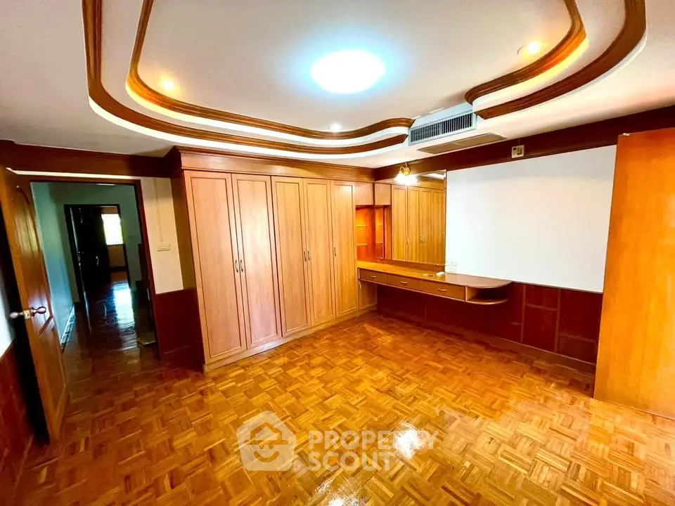 Spacious bedroom with wooden flooring and built-in wardrobes