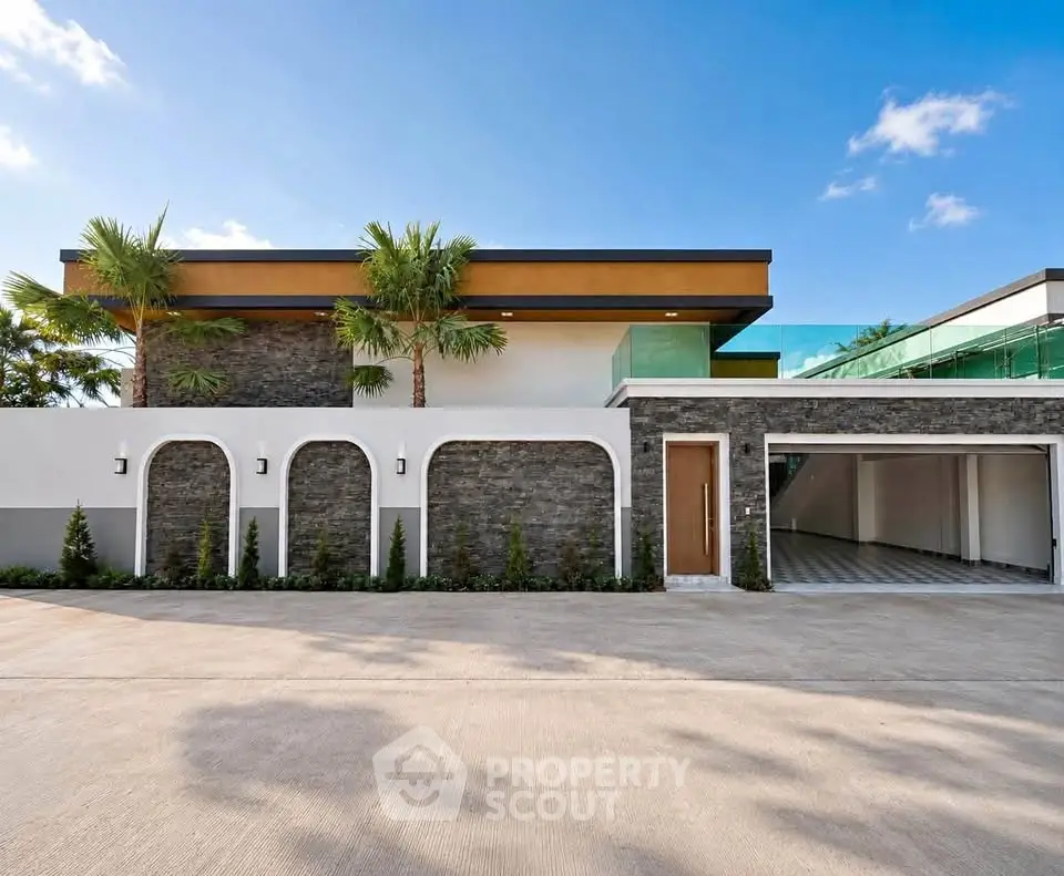 Modern luxury home exterior with sleek design and spacious garage under clear blue sky.