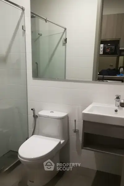 Modern bathroom with glass shower and sleek fixtures in contemporary apartment.