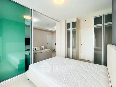 Modern bedroom with glass partition and spacious living area in contemporary apartment.