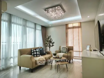 Elegant living room with modern chandelier, cozy seating, and large windows for natural light.