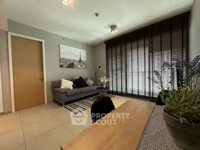 Modern living room with stylish decor and large window blinds, featuring a cozy sofa and wooden dining table.
