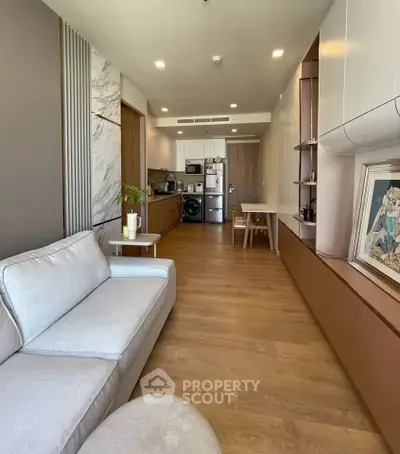 Modern living room with open kitchen, featuring sleek design and wooden flooring, perfect for urban living.