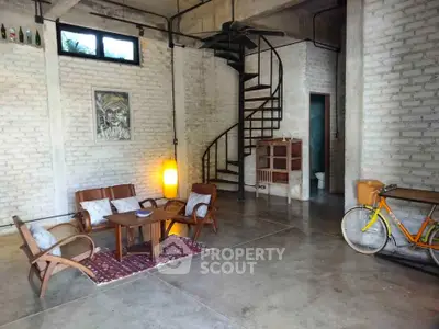 Stylish industrial loft with spiral staircase and cozy seating area.