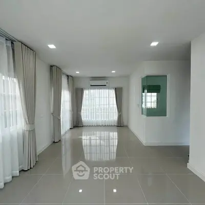 Spacious empty living room with large windows and modern tile flooring.