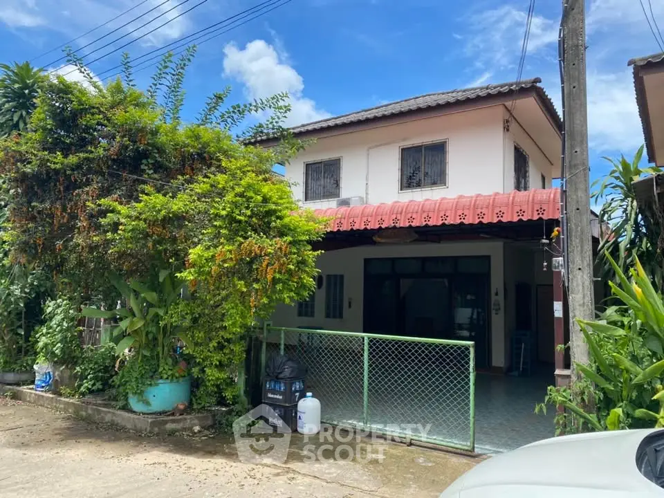 Charming two-story house with lush greenery and gated entrance in a serene neighborhood.