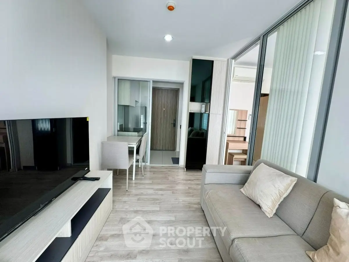 Modern living room with sleek furniture and open layout, featuring a large TV and cozy sofa.