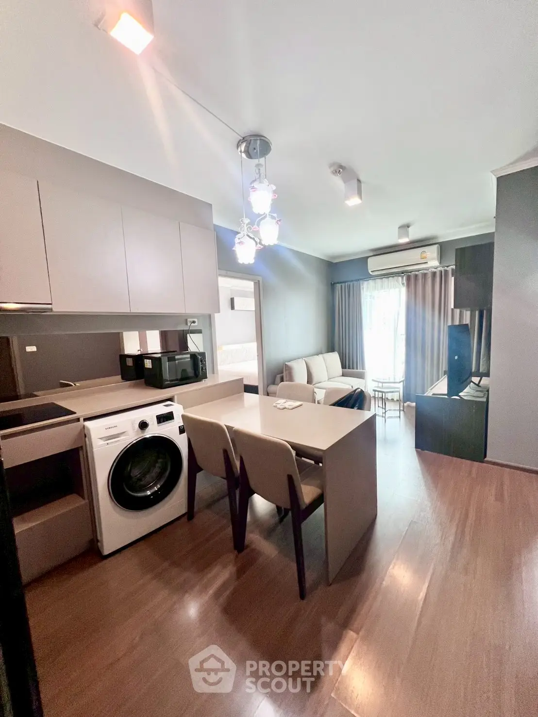 Modern open-layout living room with kitchen, featuring washing machine and stylish decor.
