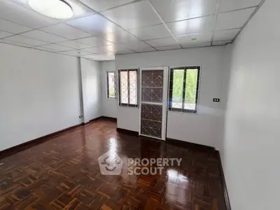 Spacious room with polished wooden floors and large windows for natural light.