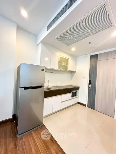 Modern kitchen with sleek cabinetry and stainless steel fridge in a stylish apartment.