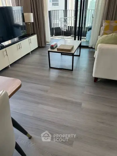 Modern living room with sleek flooring and balcony view, featuring stylish furniture and natural light.