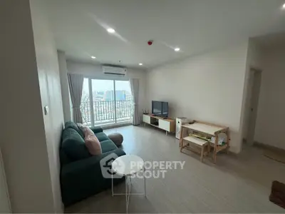 Spacious living room with modern decor and city view, featuring a cozy sofa and entertainment unit.