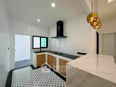 Modern kitchen with sleek design, featuring a gas stove and stylish lighting fixtures.