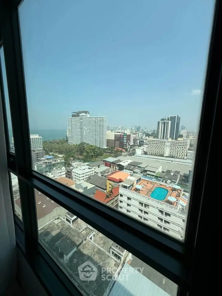 Stunning cityscape view from high-rise window overlooking urban skyline and distant sea.